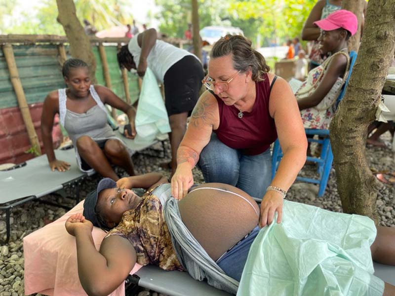 MamaBabyHaiti-Founder-Patricia Patricia Couch Mama Baby Haiti Founder. Image of Patricia measuring the belly of a pregnant woman.